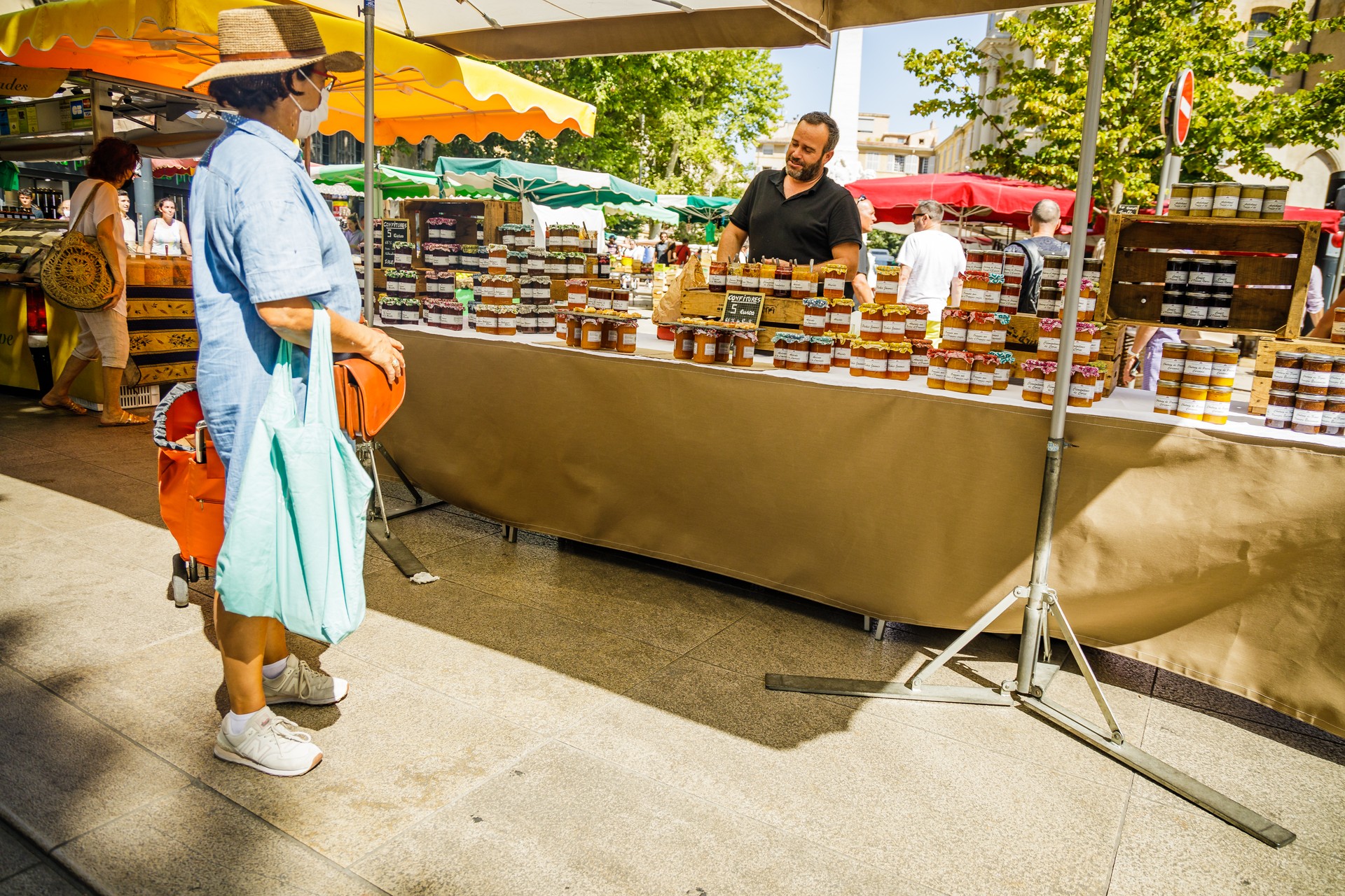 Woman talking to a merchant at a jam stand on the traditional Aix en Provence food market